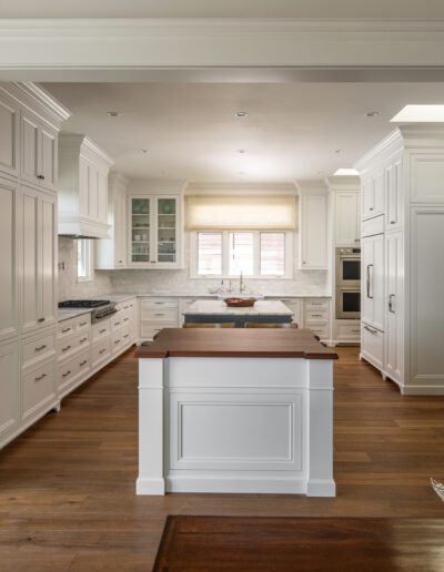 A white kitchen with wooden floors and a center island.