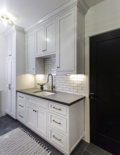 A white kitchen with black cabinets and a black door.