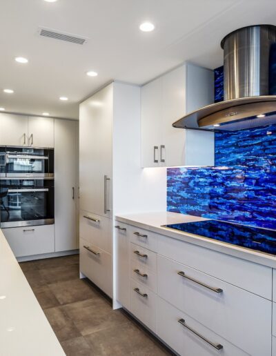 A modern kitchen with blue glass backsplash.
