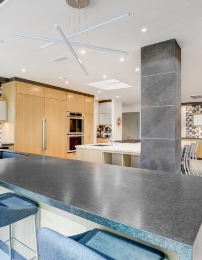 A modern kitchen with a skylight and bar stools.
